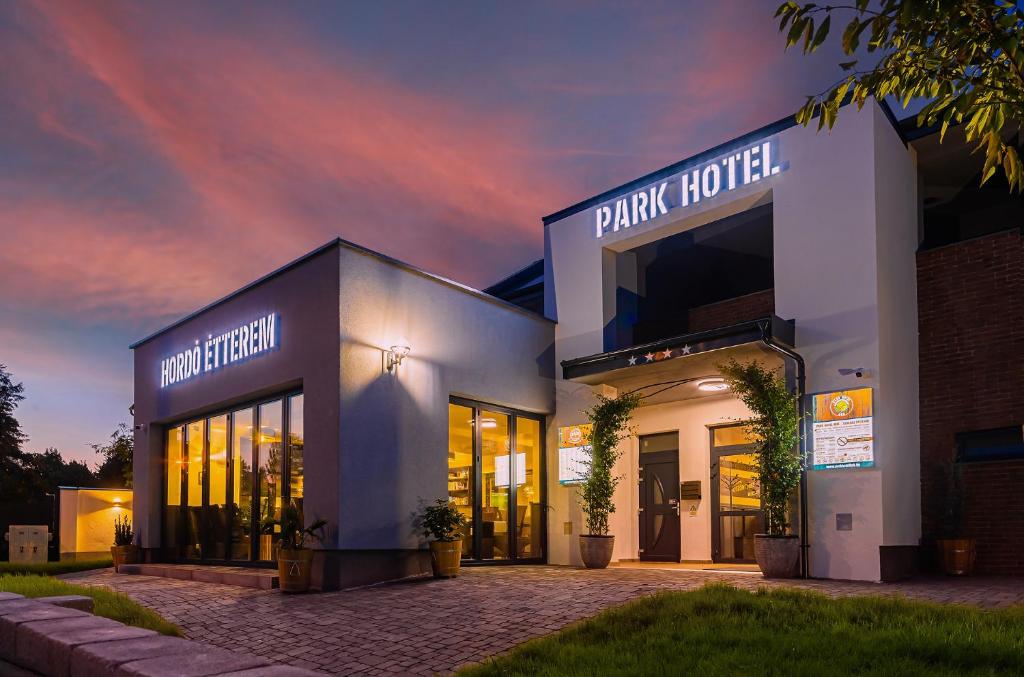 比克Park Hotel Bük-Bükfürdő的白色的建筑,上面标有黑暗的酒店标志