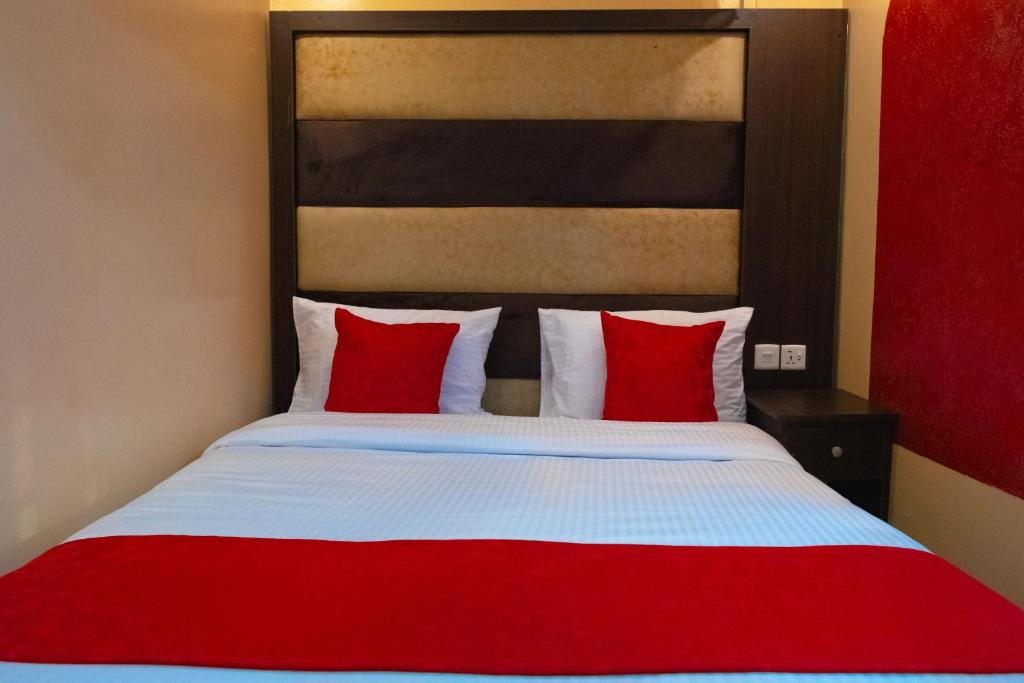 KikuyuGardens Executive Suites的卧室配有红色和白色的床和红色枕头