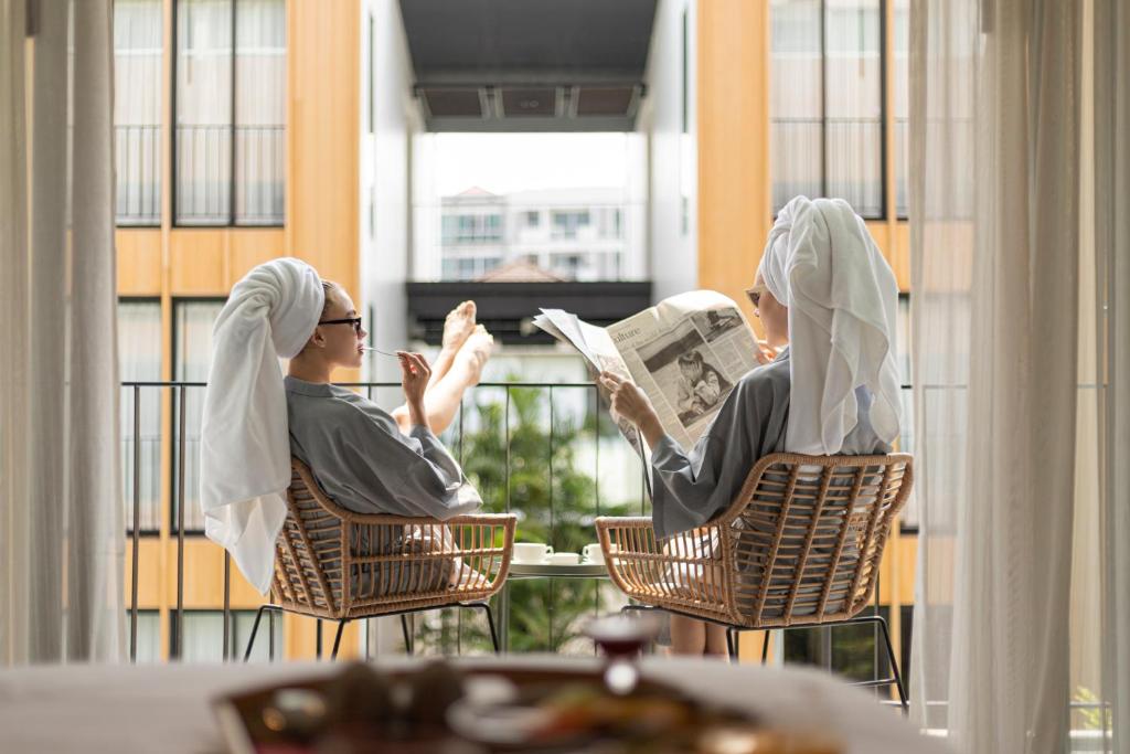 曼谷曼谷工匠酒店的两人坐在椅子上,在阳台上看报纸