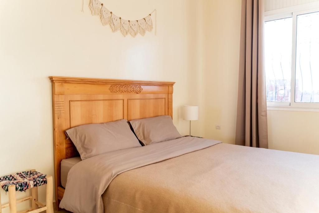 Tamraght Ou FellaCasa Janoub Morocco的一间卧室配有一张带木制床头板的床和窗户。