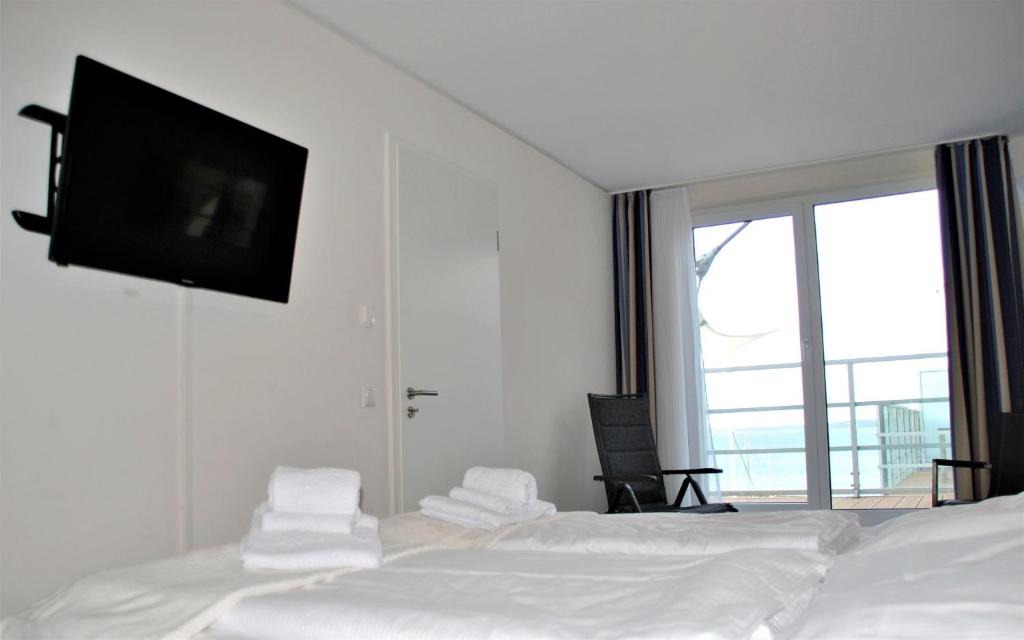 埃肯弗德Apartmenthaus Hafenspitze Ap 42 "Segler", mit Sauna, Blickrichtung offene See - a72332的卧室配有一张壁挂式平面电视的床。