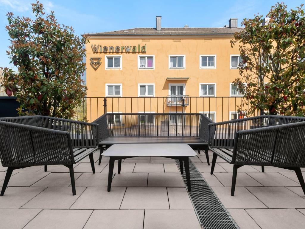 慕尼黑numa I Stark Rooms & Apartments的坐在庭院的长椅上,有一座建筑