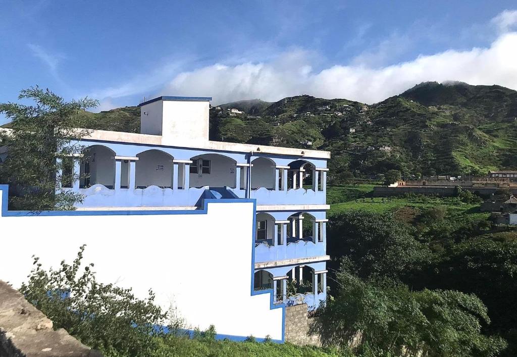 Vila Nova SintraDjabraba's Eco-Lodge的山丘上的白色建筑,背景是群山