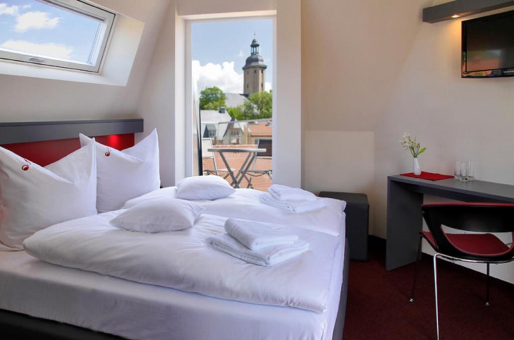 耶拿Hotel VielHarmonie的一间卧室配有带白色床单和枕头的床。