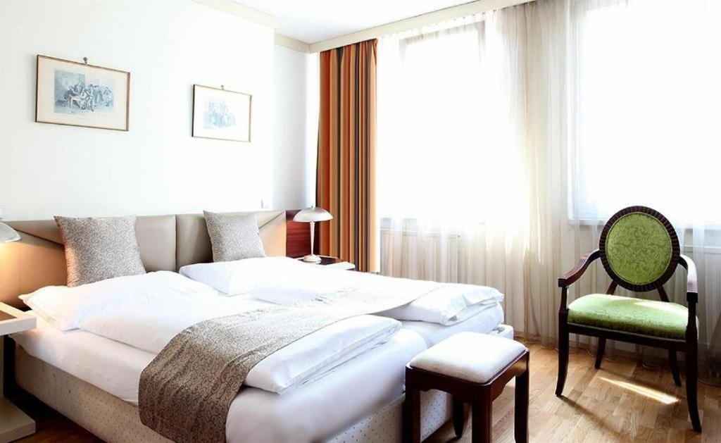 维也纳Hotel Attaché contactless的一间卧室配有一张大床和一把椅子