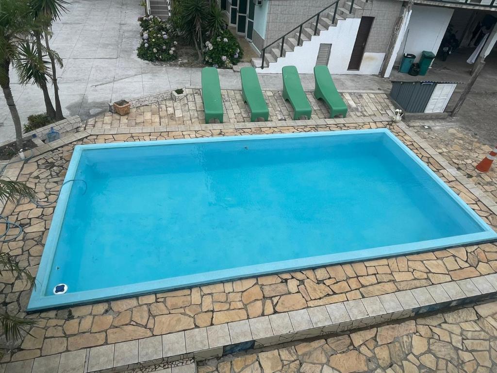 特拉曼达伊Hotel Central Praia的一座带绿色椅子的蓝色游泳池位于房子前