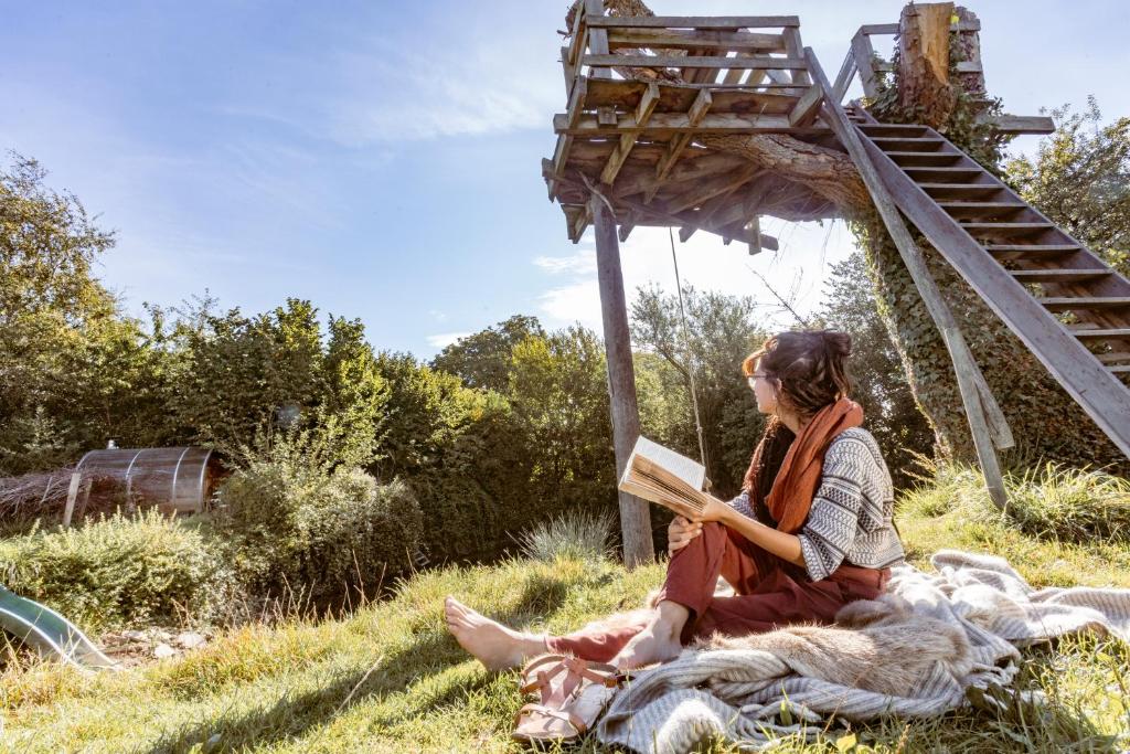 赫纲兰德Vakantiewoning met sauna & hottub en zwempoel op Natuurterrein的坐在草地上读书的女人