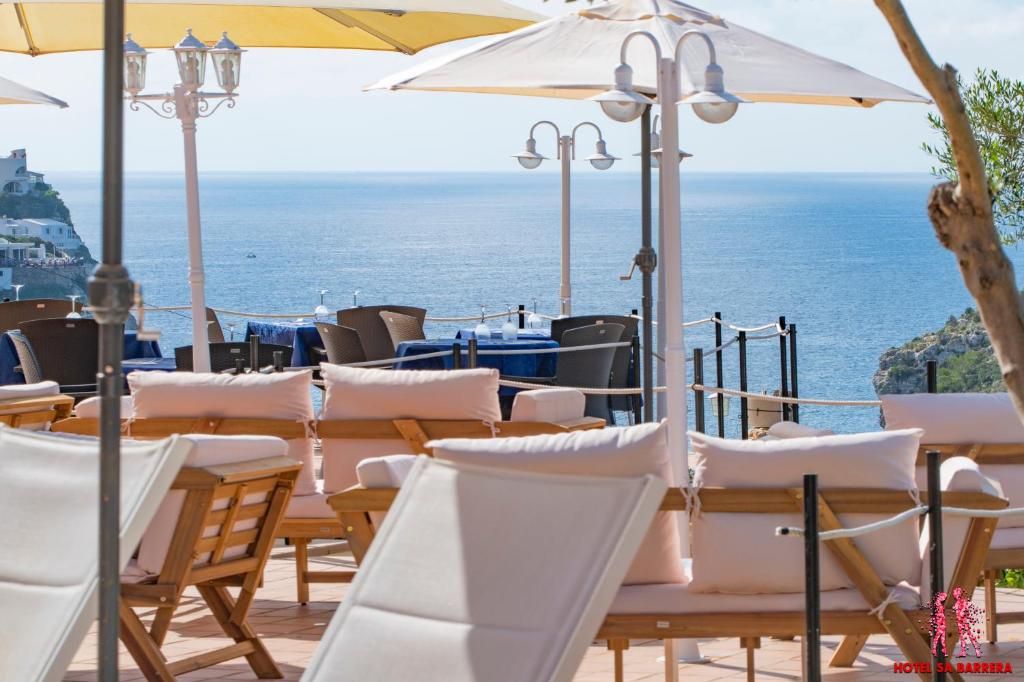 卡拉恩波特Hotel Sa Barrera - Adults Only的一组桌子和椅子,背景是海洋