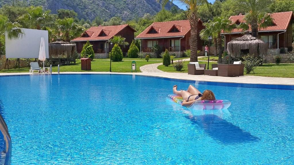 阿德拉桑阳光村庄俱乐部酒店的躺在游泳池里的木筏上的女人