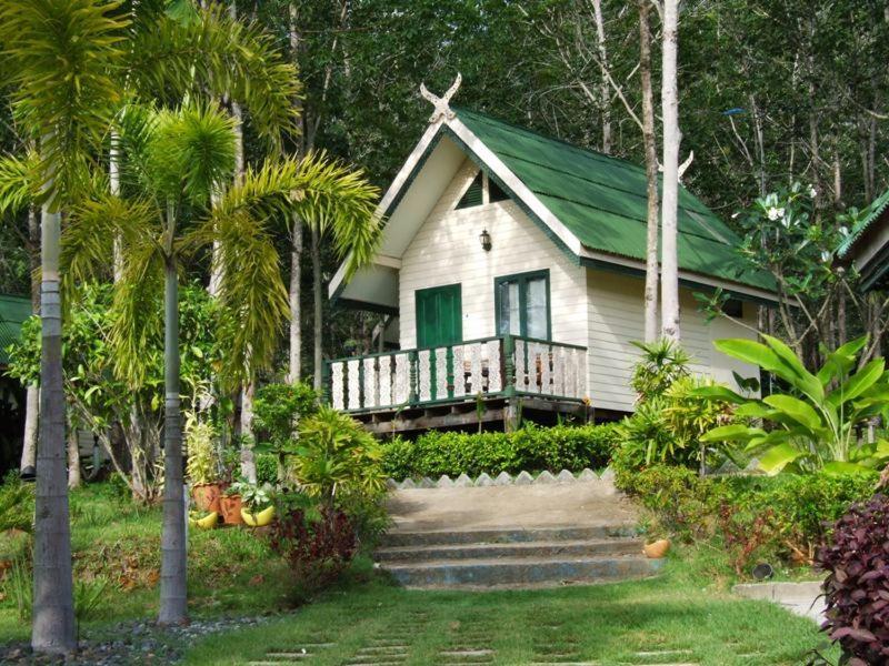 象岛帕拉度假酒店的一座白色的小房子,设有绿色屋顶