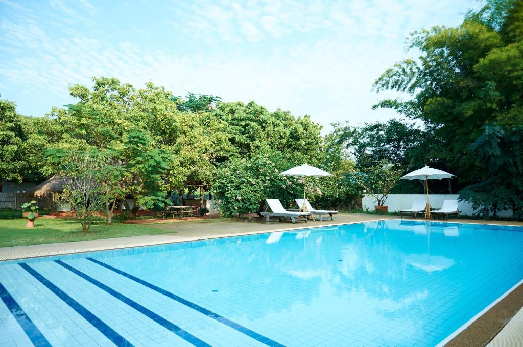 清迈resort hoshihana的一个带两把椅子和遮阳伞的大型蓝色游泳池