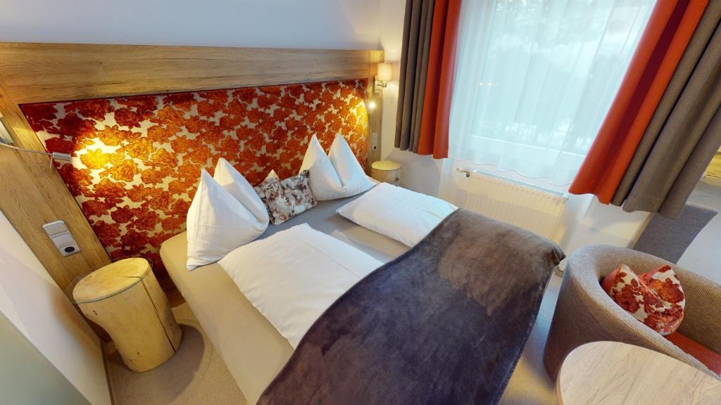 海利根布卢特拉格尔膳食公寓的配有一张床和一把椅子的酒店客房