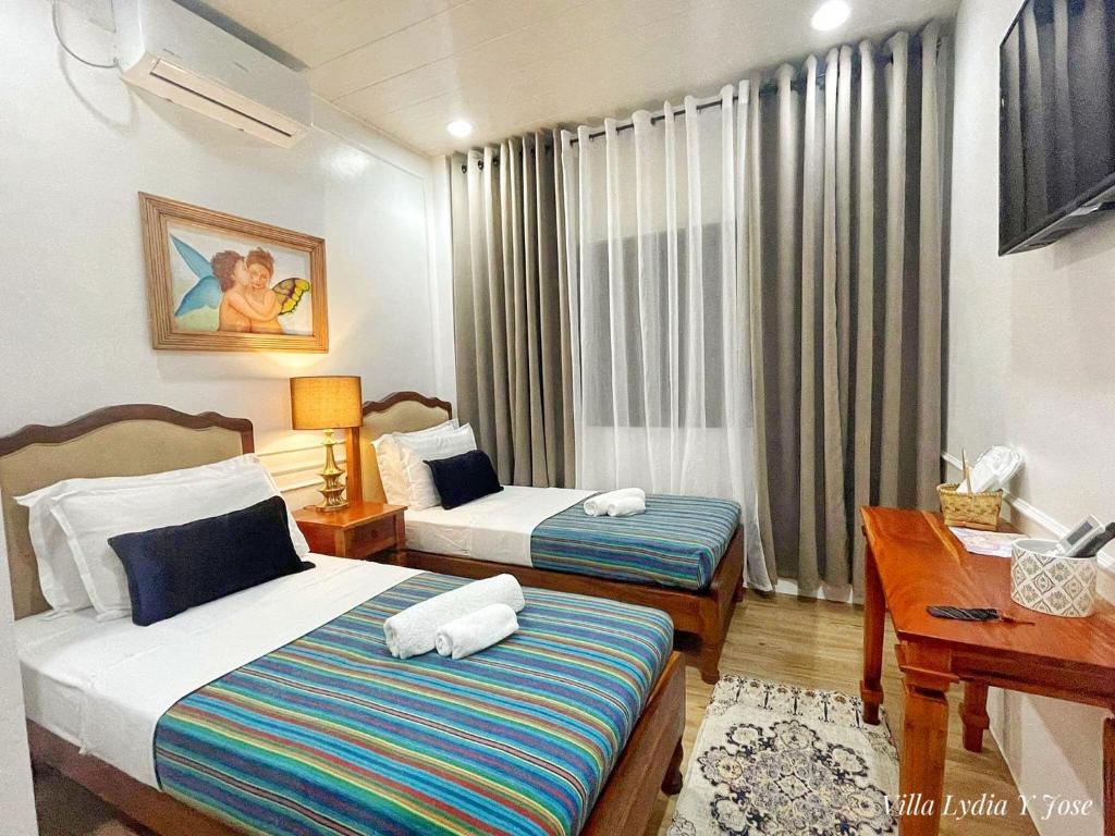 Bayubay SurVilla Lydia y Jose Heritage Hotel的酒店客房配有两张床和一张书桌