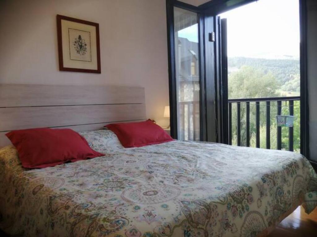 普拉德埃米塔Apartamento con jardín y luminoso Besiberri 6的一间卧室配有一张带红色枕头的床和一个阳台