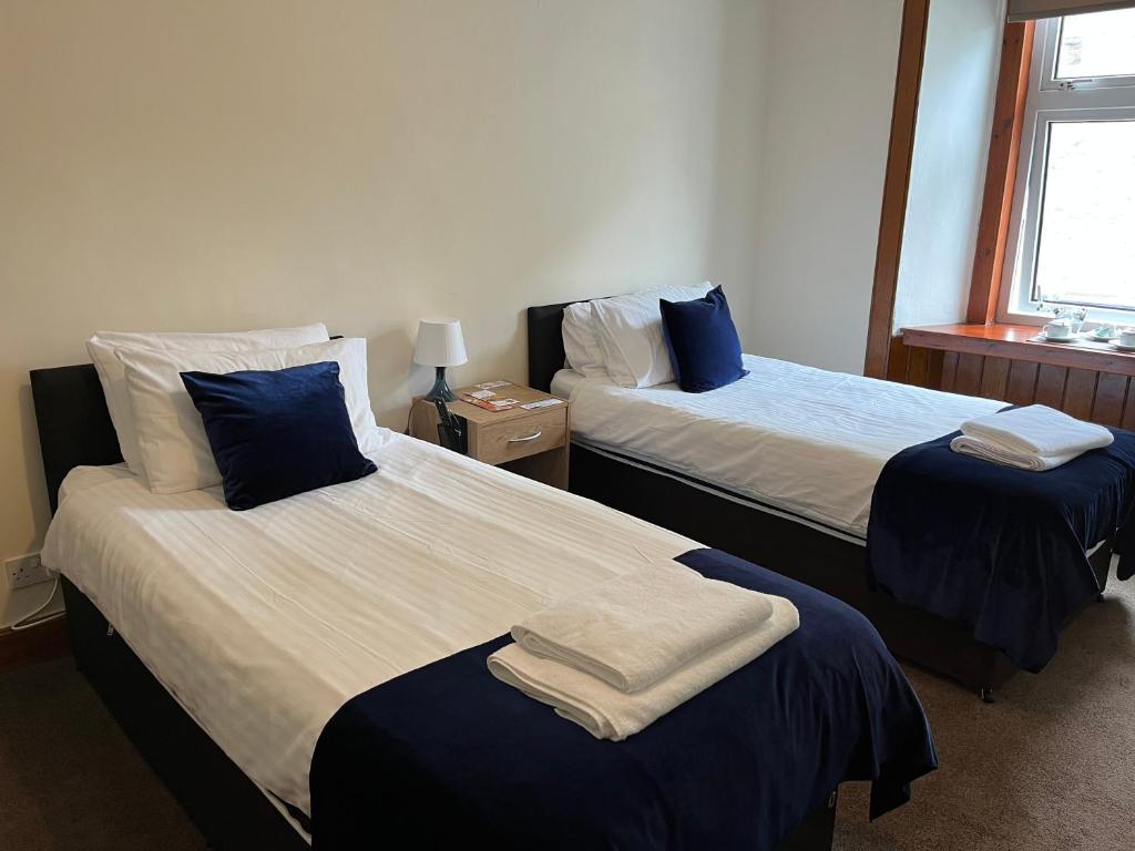 威克Caithness Inn的一间卧室配有两张带蓝白色床单的床