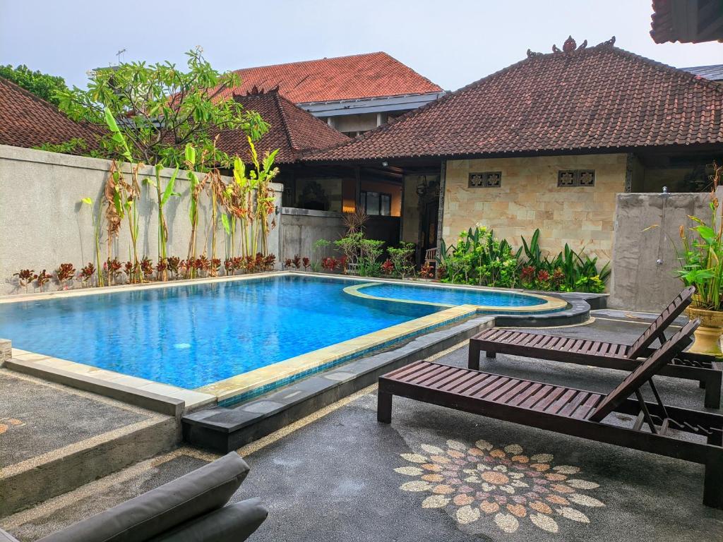 库塔Taman Sari Cottages的一个带两个长椅的游泳池