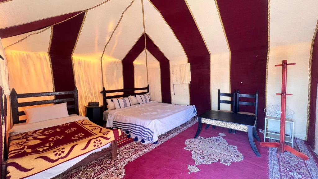 扎古拉Sahara Luxury Camp的一间设有两张床的客房,墙上有一个十字架