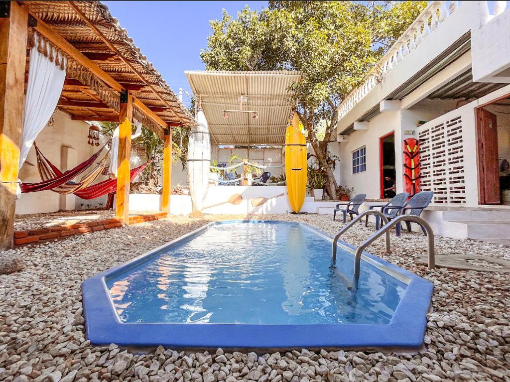 塔甘加Hostal Palohe Taganga的后院的游泳池,配有椅子和吊床