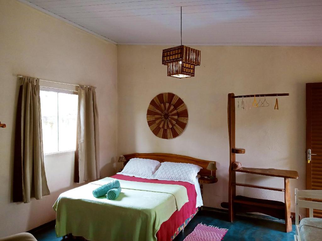 戈亚斯州上帕莱索Villa Ágape - Chapada dos Veadeiros的一间卧室设有一张床、一个窗户和一个吊灯。