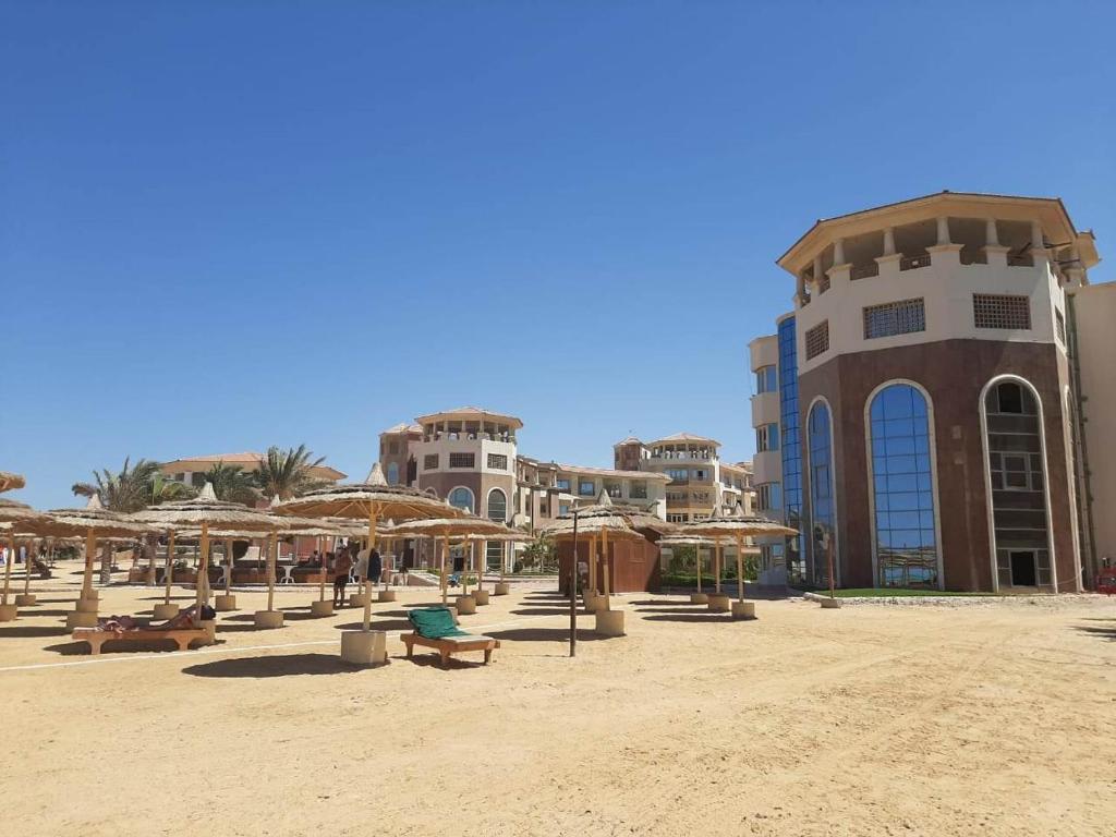 赫尔格达Tony's Privy One bed by Red Sea的一个带遮阳伞和椅子的海滩和一座建筑