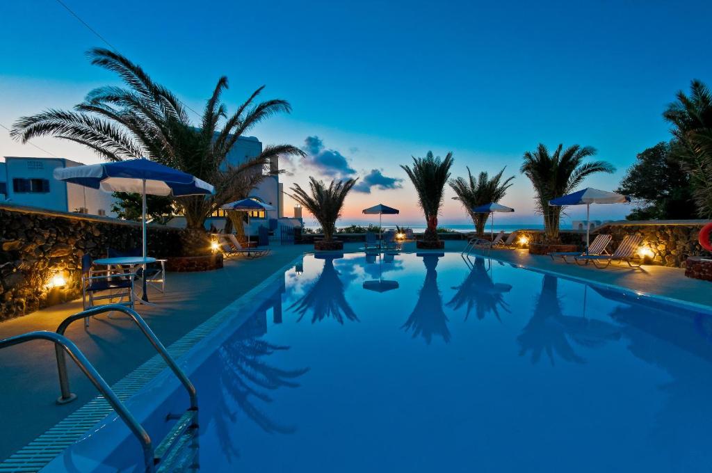 卡特瑞杜斯亚缇米斯田园酒店的棕榈树和遮阳伞的夜间游泳池