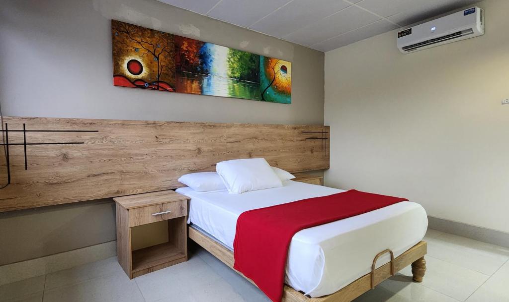 瓜亚基尔Hotel Murali - Cerca del Aeropuerto de Guayaquil的卧室配有一张床,墙上挂有绘画作品