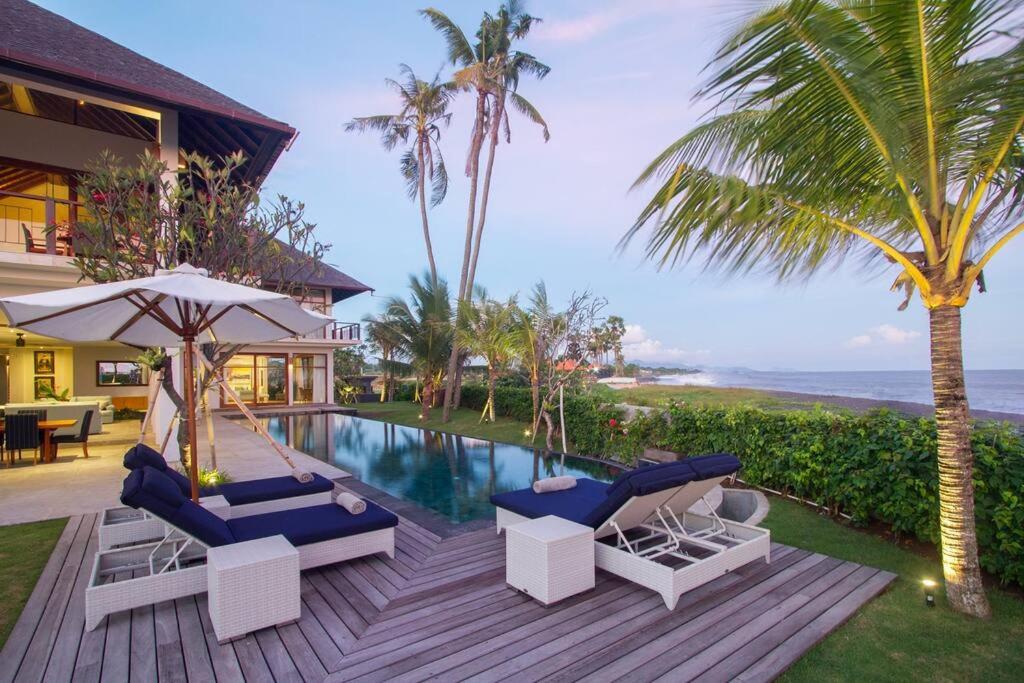 KetewelBeachfront Luxury, Villa Purnama的房屋旁的游泳池配有椅子和遮阳伞