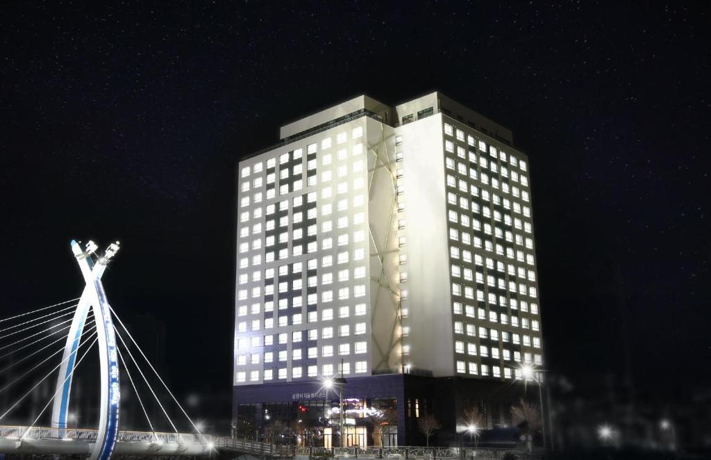 平昌艾姆酒店的一座高大的建筑,晚上有窗户照亮