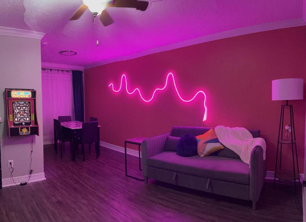 休斯顿Cozy houston Getaway 1 bed 1 bath的客厅配有带 ⁇ 虹灯标志的紫色墙壁