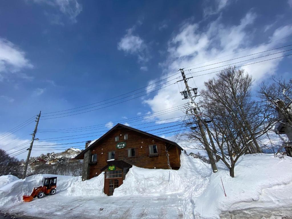 饭山市斑尾白兔度假屋的雪地中的木屋,前面有雪地车