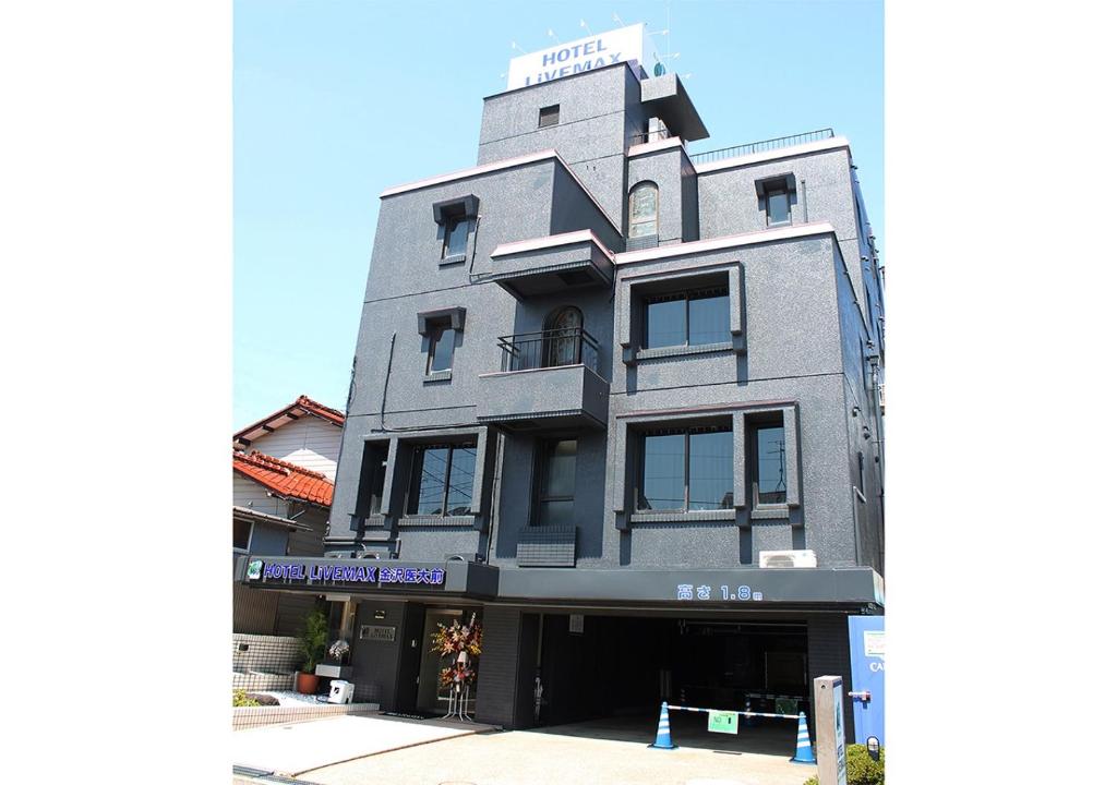 UchinadaHotel Livemax BUDGET Kanazawa-Idaimae的一座高大的灰色建筑,上面有标志