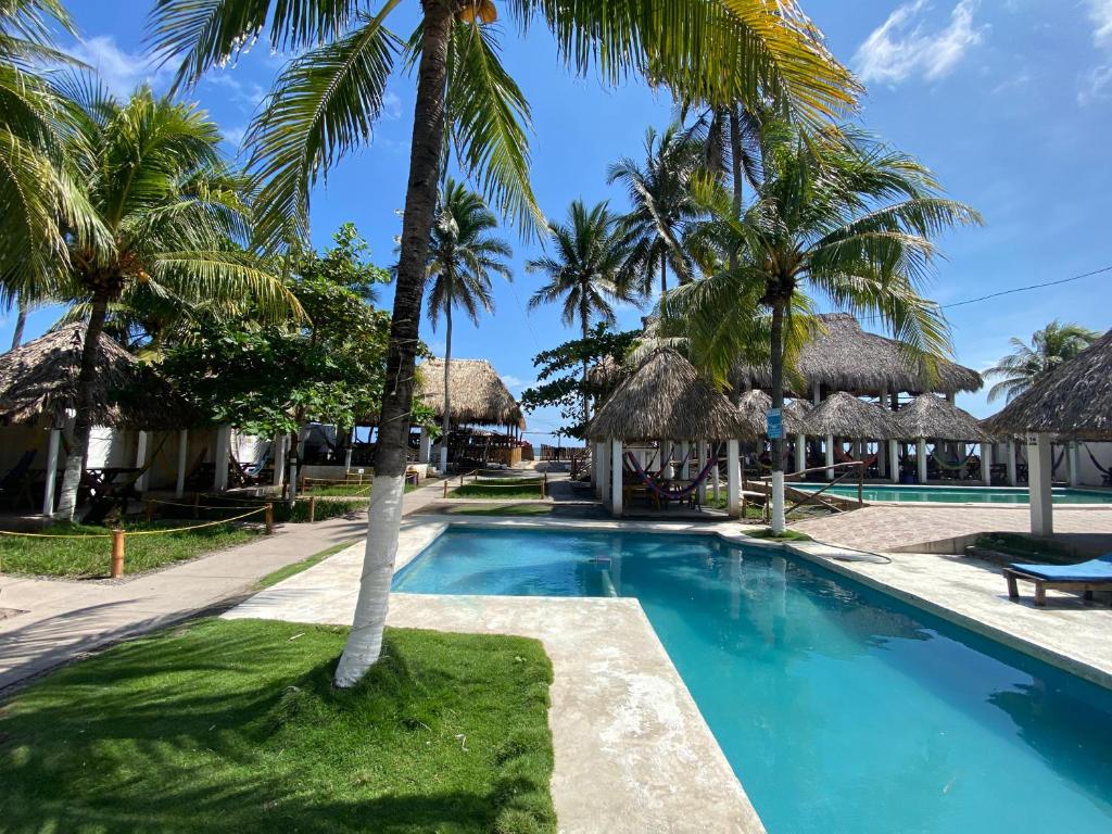 La PazHotel Paseo del Sol的棕榈树和小屋的游泳池