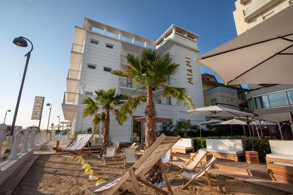 贝拉里亚-伊贾马里纳Miami Suite的一座建筑前的酒店拥有椅子和棕榈树
