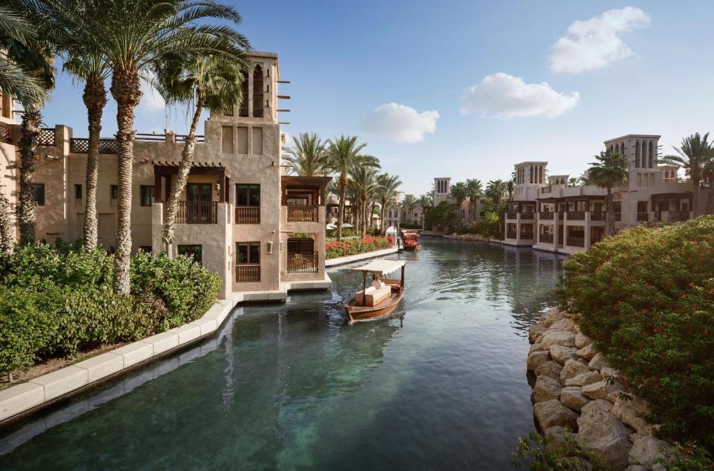 迪拜Jumeirah Dar Al Masyaf Dubai的棕榈树城市里一条带船只的运河