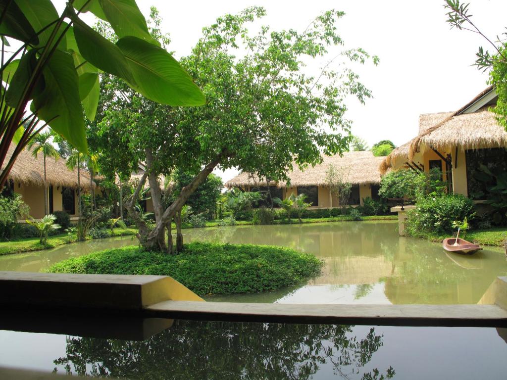 巴吞他尼荫娜特度假酒店的一座花园,在一座建筑前设有一个池塘