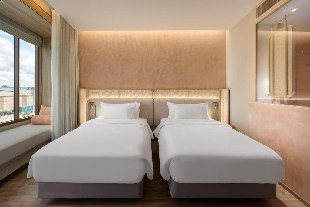 乌汶Centara Ubon的两张睡床彼此相邻,位于一个房间里