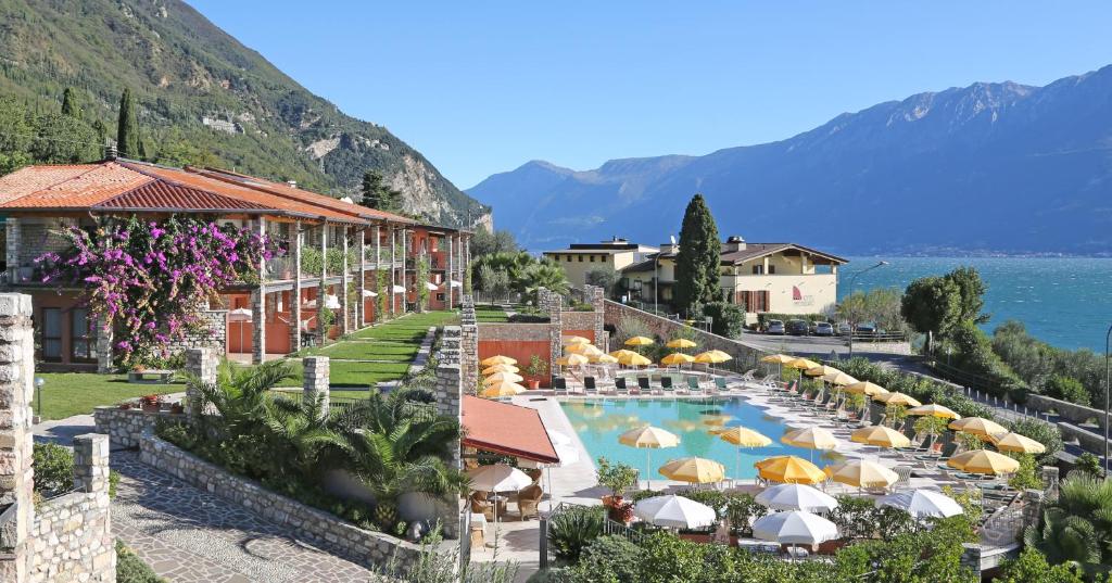 加尔尼亚诺Residence Borgo Dei Limoni - Appartamenti con Garage的一个带遮阳伞的游泳池的度假酒店