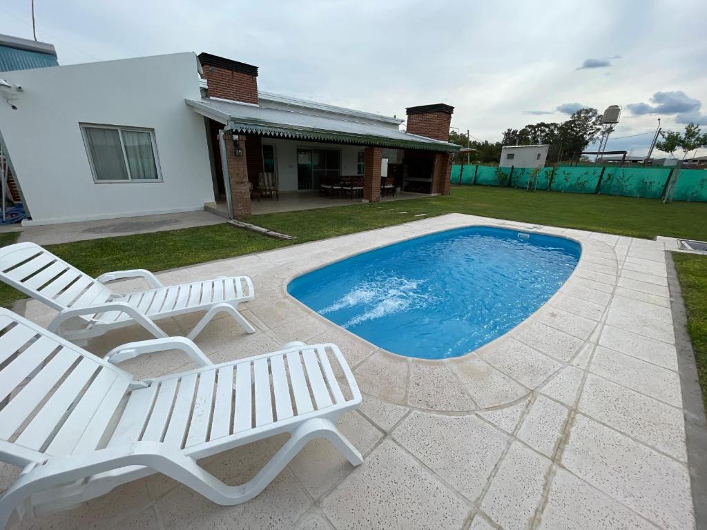 乌拉圭河畔康塞普西翁Casa quinta La Justina的一个带两把椅子的庭院和一个游泳池