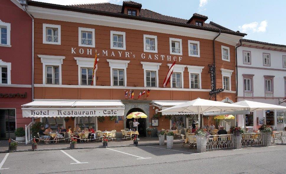 格明德Hotel Gasthof Kohlmayr的大楼前有桌子和遮阳伞的酒店