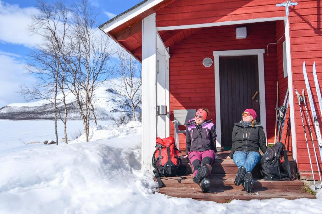 基尔匹斯扎我维基尔皮雅文雷凯里克库斯山林小屋的两个人坐在红房子外的雪里