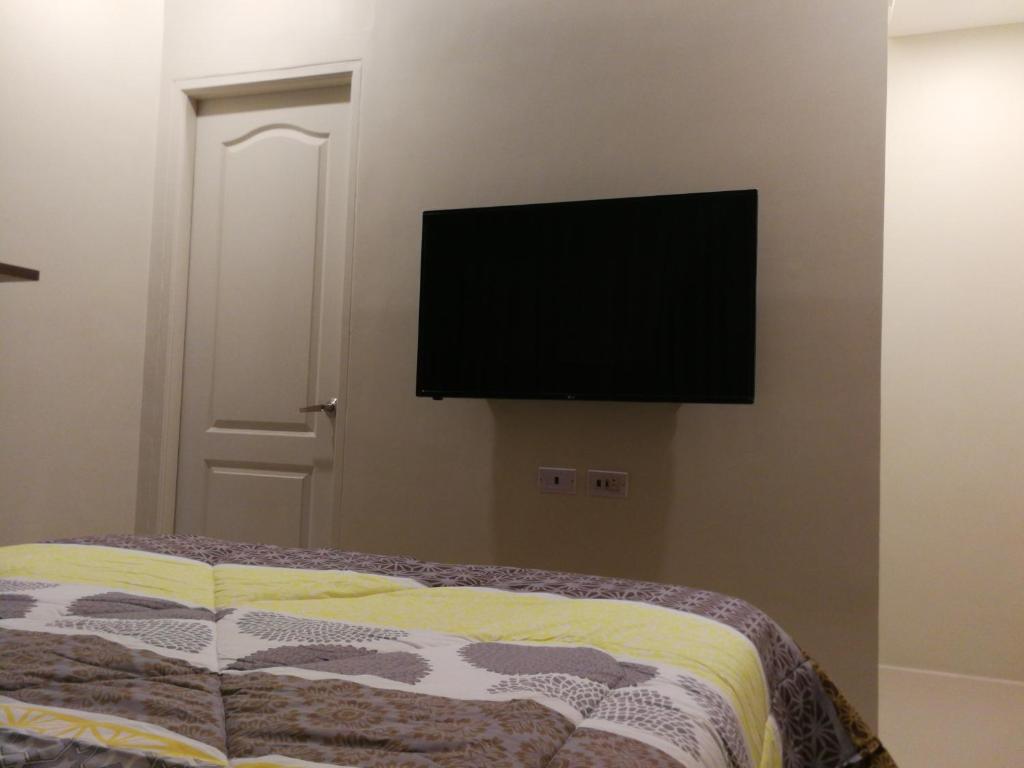 马尼拉Adria Residences - Ruby Garden - 2 Bedroom for 4 person的卧室配有一张壁挂式平面电视的床。