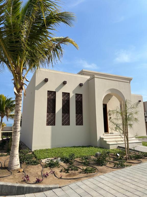 马斯喀特The Beach House的前面有棕榈树的白色教堂