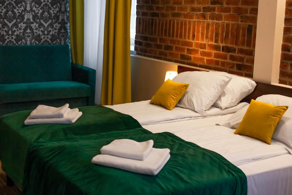 格但斯克Hotel Artus - Old Town的两张带毛巾和绿椅的床
