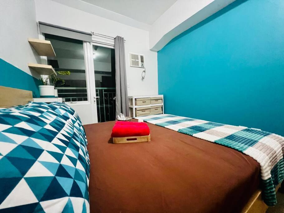 马尼拉Cozy Place Anuva Residences的蓝色卧室,配有一张床和手提箱