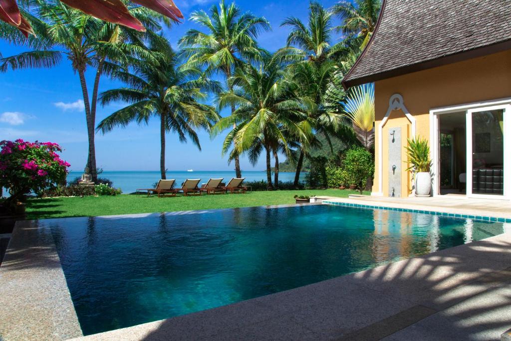 象岛Beachfront 5-bedroom Villa的棕榈树屋前的游泳池
