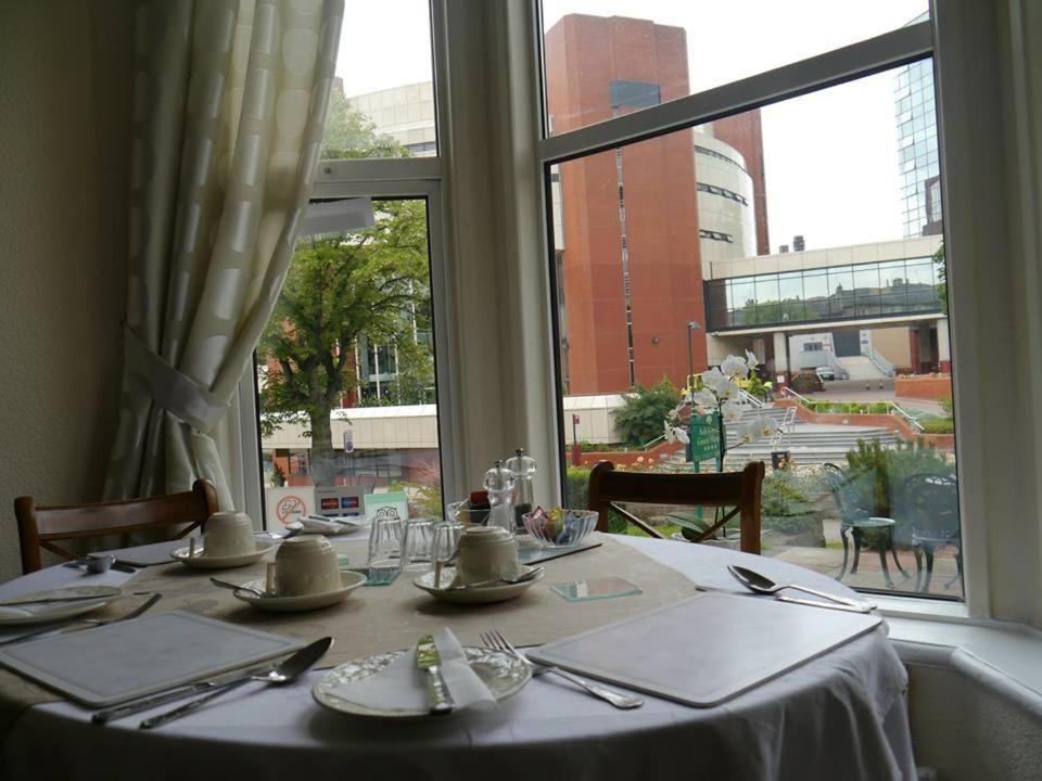 哈罗盖特孔弗伦斯家庭式旅馆的一张桌子,上面有白色的桌布和窗户