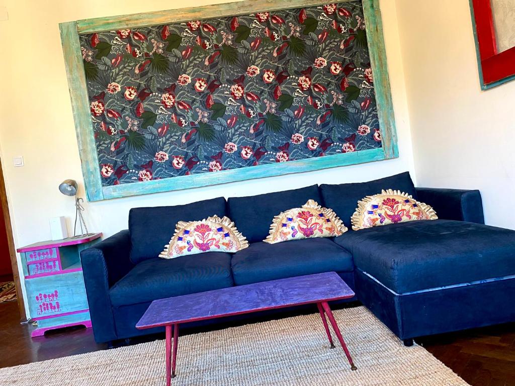 布达佩斯Lovely cosy art flat的客厅里一张蓝色的沙发,上面有大画