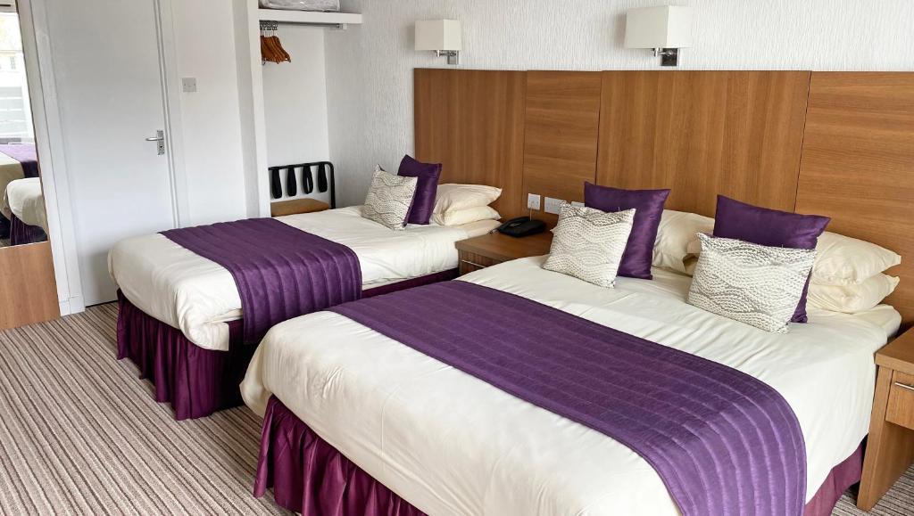 纽基Magnuson Hotel Sandy Lodge Newquay的酒店客房,配有两张带紫色床单的床