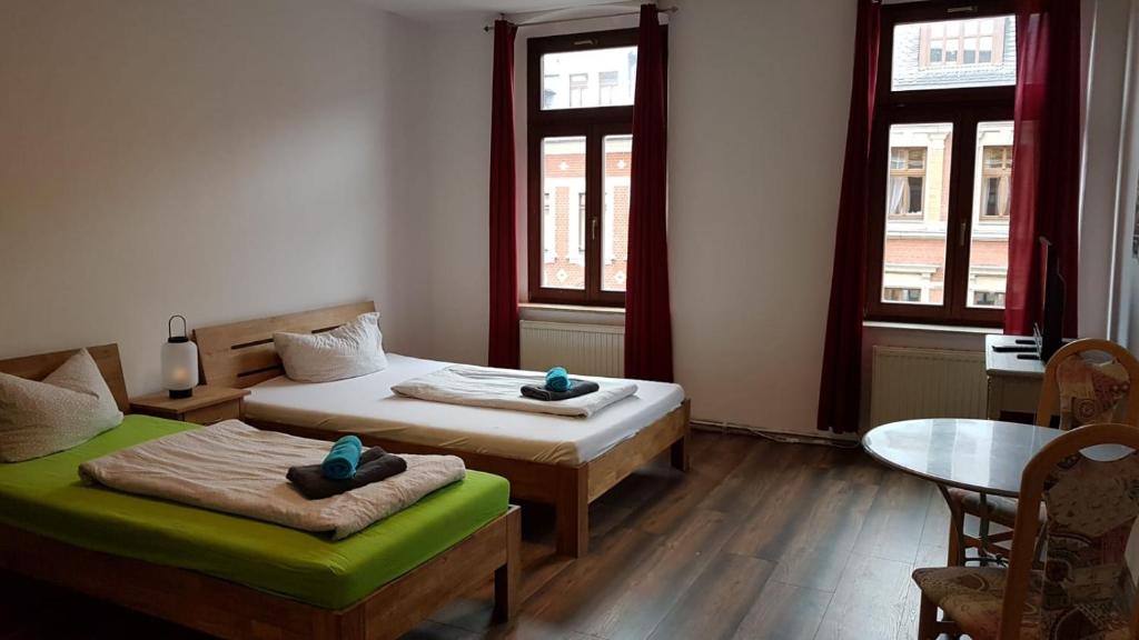 开姆尼茨凤凰旅馆的客房设有两张床、一张桌子和两个窗户。
