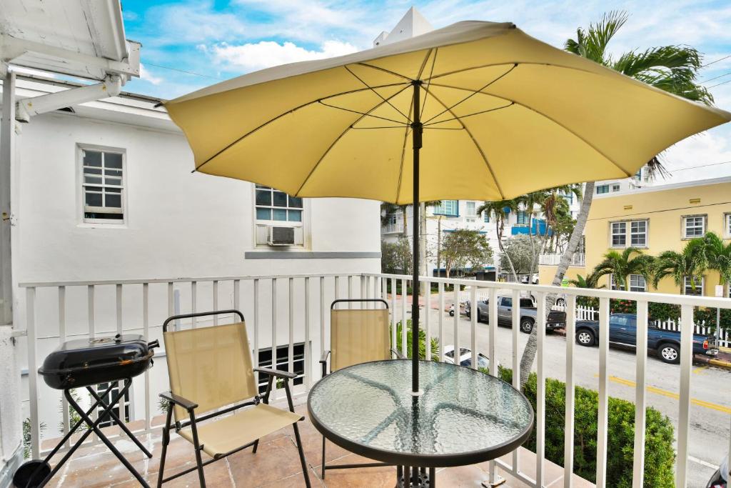 迈阿密海滩Seaheights Villa的阳台的桌椅和黄伞